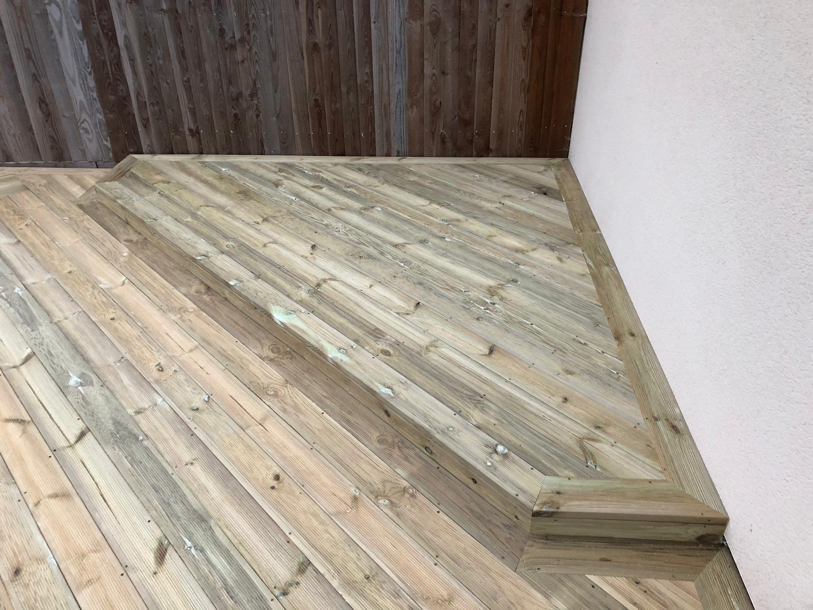 Fresh timber decking detail beside garden boundary