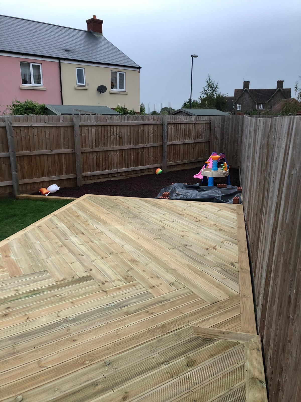 Raised timber deck with garden fencing and lawn